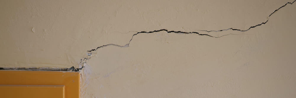 Fissure longue horizontale et profonde dans le mur beige Fissure longue horizontale et profonde dans le mur beige